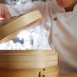 © Maxime - Chef ouvrant un panier vapeur en bambou dégageant une fumée chaude