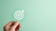 © Masque - Hand holding a green paper cut target to achieve on point business plan goals.