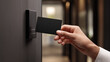 © dinatychynska - Hand holding black access card near modern electronic reader mounted on dark door, representing smart security system, contactless entry technology and corporate building access control concept.