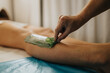 © qunica.com - A beauty center therapist peels a wax strip from a client's lower leg during a hair removal treatment. Close-up of the waxing procedure showing the therapist's hand removing wax from skin.