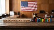© Candra - Deportation concept with wooden blocks judge gavel and colorful figures against US flag background.