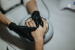 © qunica.com - A manicurist in black gloves holds a client's hand during a nail treatment. The close-up shows a nail technician performing a manicure at a salon station.
