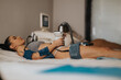 © qunica.com - A young woman lies on a treatment bed receiving a non-invasive body contouring treatment at a beauty center.