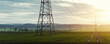 © Kyryl Gorlov - Scenic view of electricity pylons stretching across green fields warm sunset sky background. Electric power supply high voltage metal tower in Europe