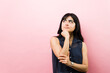 © AntonioDiaz - Latin woman contemplating on pink background, thinking seriously, making a decision, looking up for inspiration