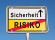 © Animaflora PicsStock - Sicherheit statt Risiko auf einem Ortsschild mit blauen Hintergrund