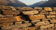 © Dedi - Rough cut slate wall with natural cleavage planes against a mountainous landscape backdrop.