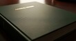 © Khaisan - A close-up view of a black leather-bound book with gold text on a wooden table indoors