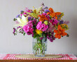 © MaskaRad - Colorful summer bouquet with lilies and garden flowers in glass vase on table, bright floral arrangement, home decor still life
