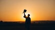 © Mr Sai - A triumphant graduate in silhouette joyfully raises their cap against the radiant golden sunset, symbolizing academic achievement and a promising future ahead.