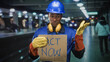 © Krakenimages.com - Man construction worker holds cardboard sign reading act now and points with gloved hand in building; urgency.