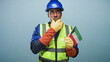 © Krakenimages.com - Man construction worker wearing hardhat reflective vest and gloves holding kuwait flag with hand on chin in studio; pride duty.