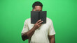 © Krakenimages.com - Man holds black book up to his face with hand, peeking eyes over the page in studio green backdrop; curiosity private study.