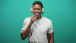 © Krakenimages.com - African american man wearing over ear headphones, smiling with right hand to chin and relaxed posture against teal seamless studio backdrop; joyful confidence.