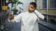 © Krakenimages.com - Man with smartphone tapping screen and pointing finger on a street while smiling in a white sweatshirt; quiet amusement.