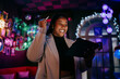 © BullRun - Smiling woman creating digital content on tablet in night club environment with colorful neon lights creative professional lifestyle authentic representation inclusion and success smiling