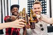 © ADDICTIVE STOCK - Friends clinking beer bottles at casual indoor party