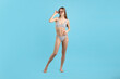 © New Africa - Beautiful woman wearing stylish swimsuit and sunglasses on light blue background