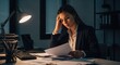 © irawan710 - Stressed Businesswoman Working Late Overtime at Desk with Papers and Lamp.