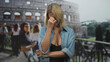 © Krakenimages.com - Woman pinches nose showing exposed cleavage at a building balcony by the colosseum, arms crossed and grimacing in public; disgust nausea.