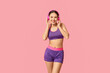 © Pixel-Shot - Young woman in sportswear listening to music on pink background