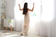 © Pixel-Shot - Morning of pretty young woman opening curtains in bedroom