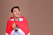 © Gatot - Indonesian Male Worker in White Uniform Looking up at Copy Space While Draped in Red and White Flag