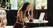 © peopleimages.com - Frustrated, woman and headache with laptop in cafe for mistake, remote work or stress. Tired, female person or freelancer with migraine or fatigue on computer for deadline or pressure in coffee shop