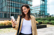 © Westend61 - Manager smiling and using smartphone outdoors in financial district