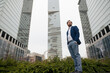© Westend61 - Businessman with hands in pockets standing near modern skyscrapers