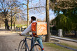© Oscar - Courier delivering food by bicycle in urban park