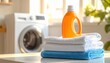 © Igor_Tichonow - Bright orange laundry detergent bottle placed on top of neatly folded white and blue towels inside clean modern washroom space