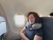 © Юлия Завалишина - Rest on plane. Young woman napping sitting by porthole in business jet using neck pillow for travel. Passenger girl flying in plane. Girl sleeping in airplane going on trip vacation. Traveling girl