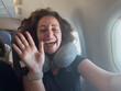 © Юлия Завалишина - Happy passenger young woman is flying in plane. Smiling girl sitting in airplane near window going on trip vacation travel. Traveling female inside plane enjoying flight. Traveling girl