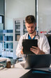 © NINENII - Male doctor working on desk with laptop computer and paperwork in the office. Medical and doctor concept.