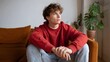 © Bussakon - A young individual sits indoors contemplating deeply while wearing comfortable casual attire in a cozy home setting