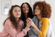© wavebreak3 - Three female friends leaning close, sharing handheld mic, singing at home wearing denim jacket
