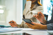 © MIND AND I - Close-Up of Businesswoman Using Smartphone at Office Desk