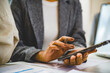 © MIND AND I - Close-Up of Businesswoman Using Smartphone at Office Desk