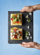 © EdienuFoto - Hands holding slate board with colorful vegetable tarts