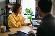 © djile - Professional woman pointing at financial charts on laptop while discussing business strategy with colleague
