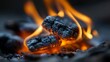 © www.freund-foto.de - Brennende Holzkohle mit orangefarbenen Flammen in einer dunklen, dramatischen Nahaufnahme
