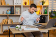 © Andrii Iemelianenko - Young man on home table checks bills with tense lips and helpless hands after unexpected payment shock. Adult guy on home table tries to review costs and manage budget stress during home money crisis.