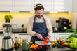 © Andrii Iemelianenko - Middle-aged man chops tomatoes for fresh salad while wearing headphones singing in home kitchen. Young guy feels happy follows healthy diet for weight loss meal prep plus simple cooking for fitness.