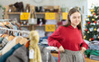 © JackF - Teenage girl buyer choosing winter trousers in clothing store decorated for christmas