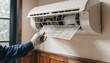 © Justlight - Closeup of minisplit air conditioner indoor unit with technicians hand changing filter focusing on seasonal preventive maintenance in a home setting.