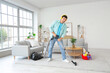 © Pixel-Shot - Young man vacuuming carpet and listening to music in room