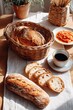 © timitinej - A dining table is set for breakfast. A basket holds fresh bread, and a plate features jam. A cup of coffee sits nearby, inviting people to enjoy the meal together
