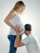 © colin - Man kneeling listening to noise in pregnant womans stomach