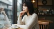 © GANBA - カフェのテーブルで外を見る女性